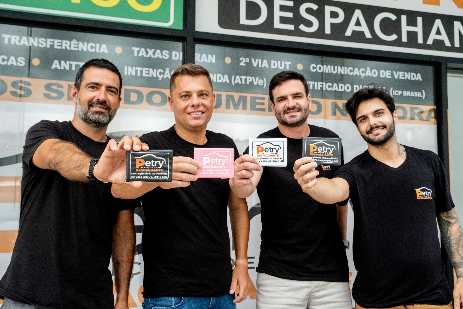 Equipe da Petry Despachante (da esquerda para a direita: Saulo, Anisio Petry, Renan e Luiz Arthur) em frente à vitrine com a lista de serviços